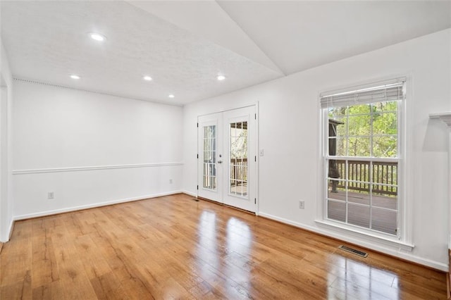 spare room featuring hardwood / wood-style flooring, french doors, visible vents, and plenty of natural light