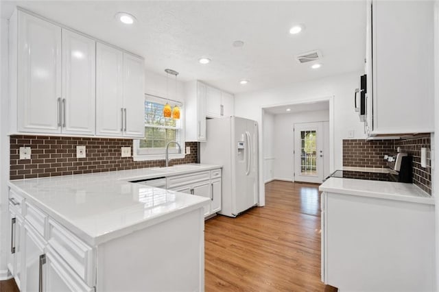 kitchen with white fridge with ice dispenser, stove, white cabinets, visible vents, and a sink