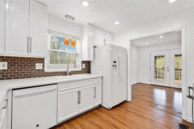 kitchen featuring white appliances, light wood-type flooring, a sink, and white cabinetry