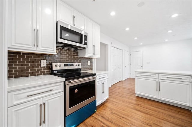 kitchen with stainless steel appliances, tasteful backsplash, light wood-type flooring, and white cabinetry