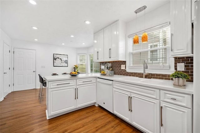 kitchen with light wood-style flooring, a peninsula, a sink, and white dishwasher