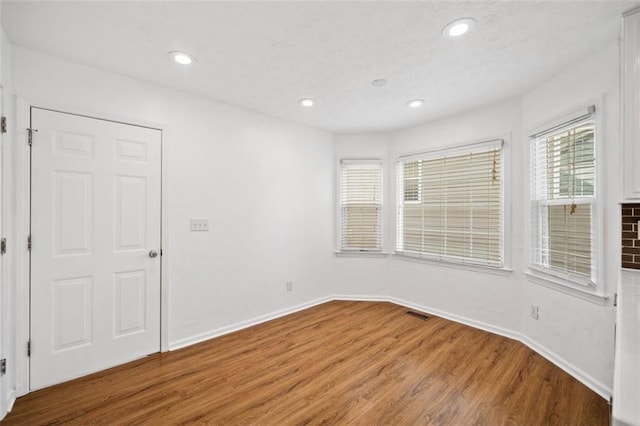 empty room featuring visible vents, baseboards, recessed lighting, and wood finished floors