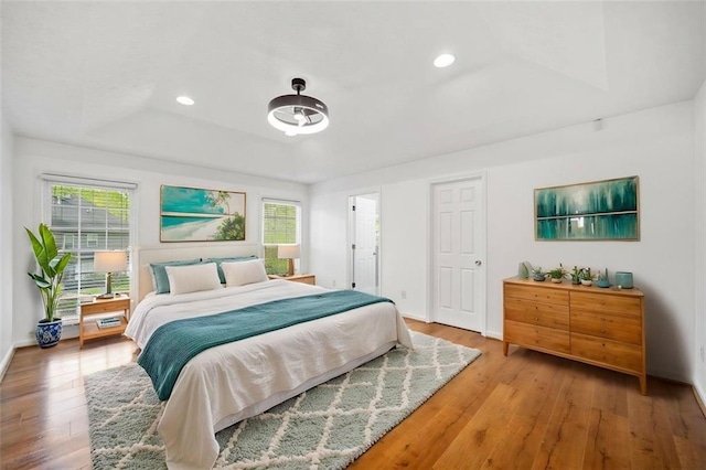 bedroom featuring a tray ceiling, baseboards, recessed lighting, and wood finished floors