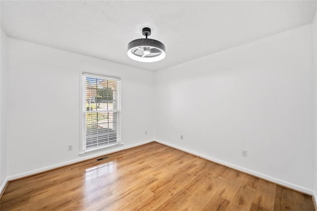 empty room featuring visible vents, baseboards, and wood finished floors