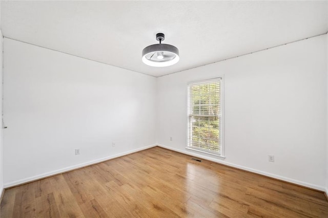 empty room featuring visible vents, baseboards, and wood finished floors