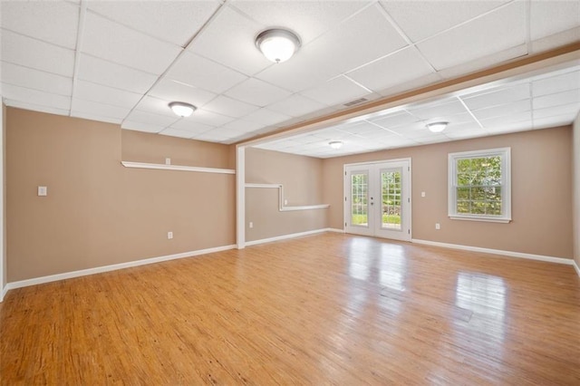 spare room featuring light wood-style flooring, a paneled ceiling, and baseboards