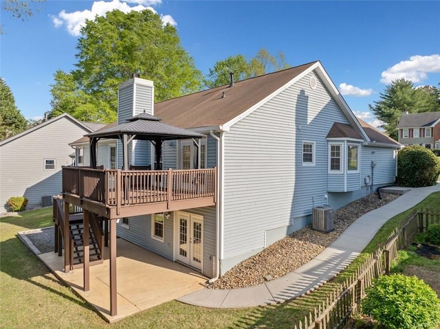rear view of property featuring a wooden deck, a chimney, a patio, a gazebo, and french doors