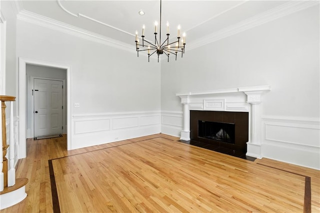 4011 Charrwood Trce, Marietta, GA 30062 - unfurnished living room with crown molding, wood finished floors, a chandelier, a fireplace, and a wainscoted wall