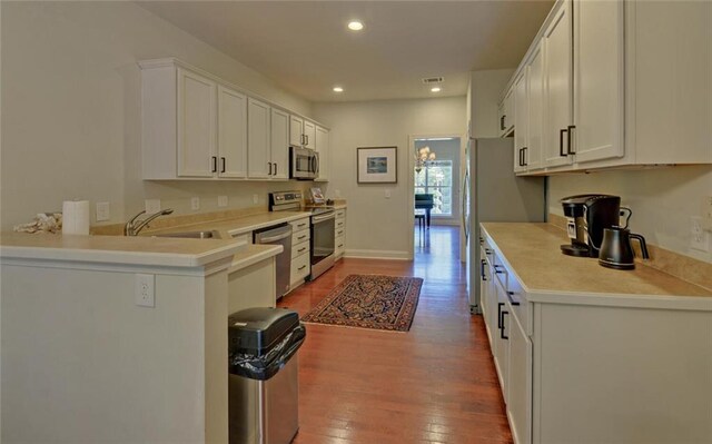 kitchen with hardwood / wood-style flooring, stainless steel appliances, sink, and white cabinetry