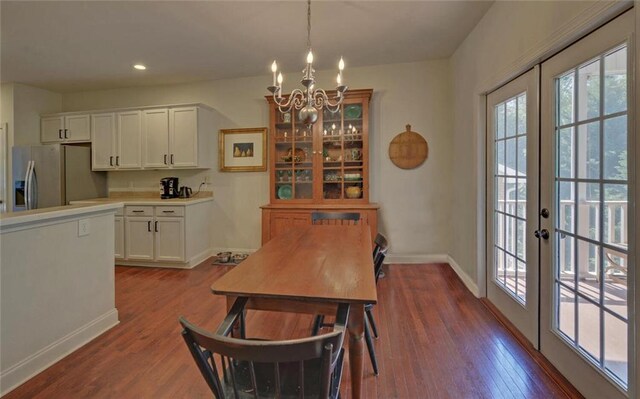 dining space with wood-type flooring, an inviting chandelier, and french doors