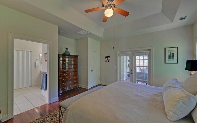 bedroom featuring light wood-type flooring, access to exterior, a raised ceiling, ceiling fan, and french doors