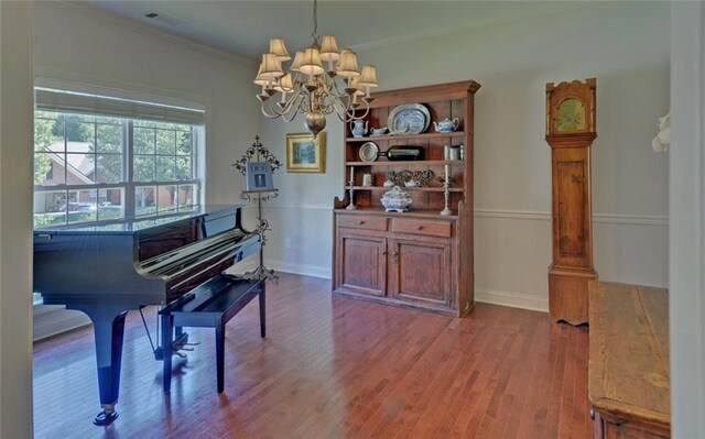 miscellaneous room featuring a notable chandelier, crown molding, and hardwood / wood-style floors