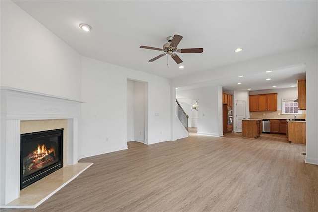 unfurnished living room with light wood-style flooring, recessed lighting, stairway, a fireplace, and baseboards