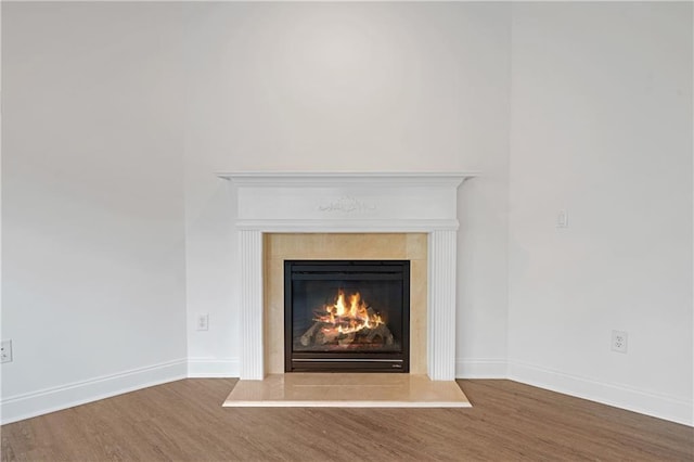 interior details with baseboards, a lit fireplace, and wood finished floors