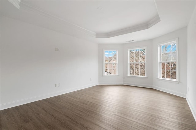 spare room featuring a tray ceiling, dark wood-style floors, baseboards, and ornamental molding