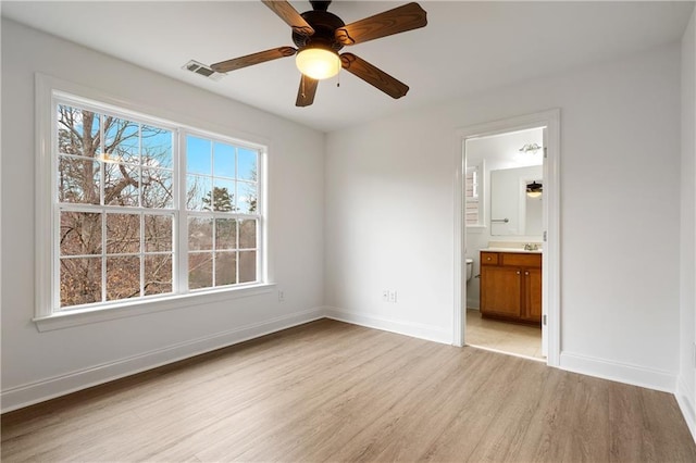 unfurnished bedroom with connected bathroom, light wood-style floors, visible vents, and baseboards