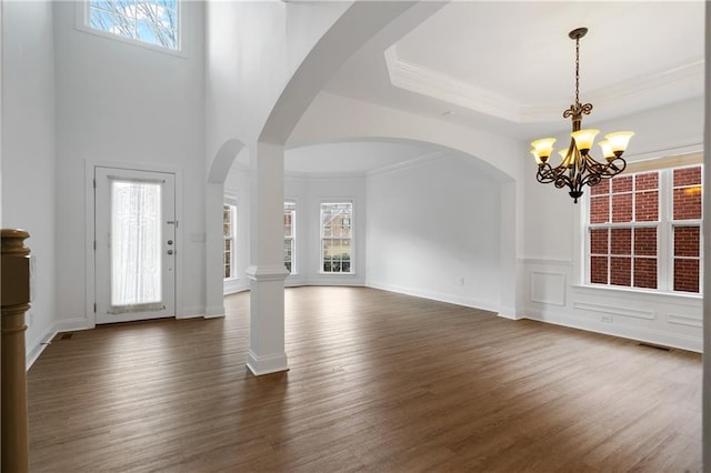 foyer entrance with plenty of natural light, a raised ceiling, crown molding, and dark wood-style flooring