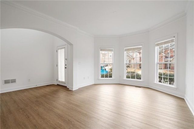 unfurnished room with visible vents, baseboards, light wood-style floors, and ornamental molding