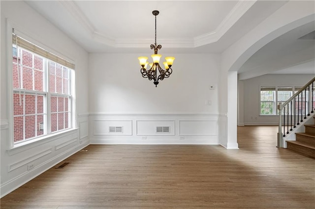 spare room featuring arched walkways, visible vents, stairs, and a tray ceiling