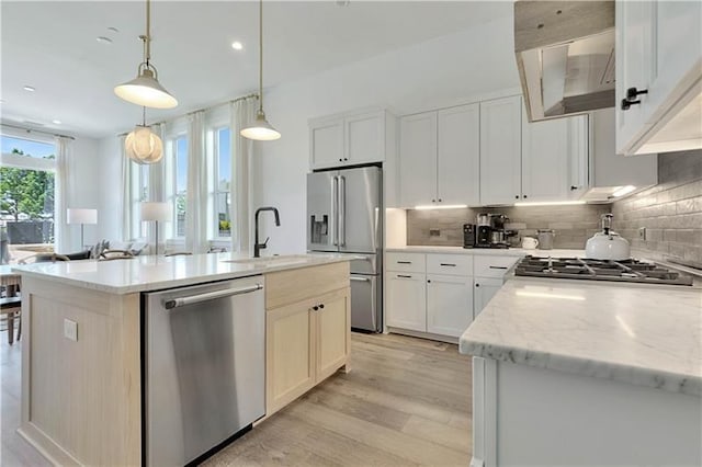 kitchen featuring appliances with stainless steel finishes, a sink, light wood-style flooring, and decorative backsplash