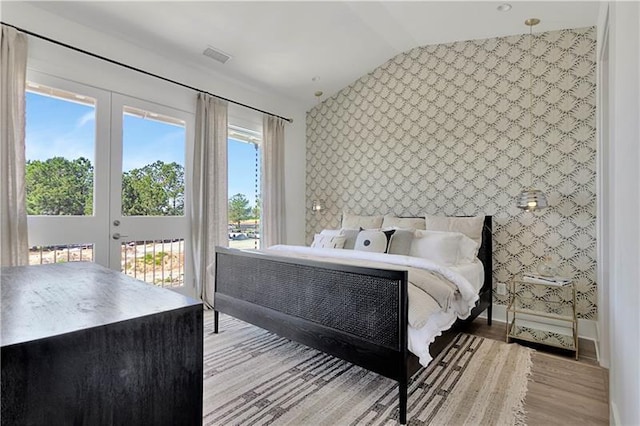 bedroom featuring lofted ceiling, wood finished floors, access to outside, baseboards, and wallpapered walls