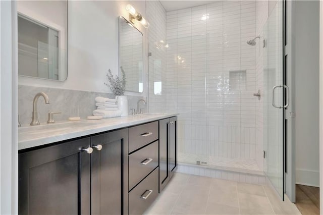 bathroom featuring tile patterned floors, a sink, a shower stall, and double vanity