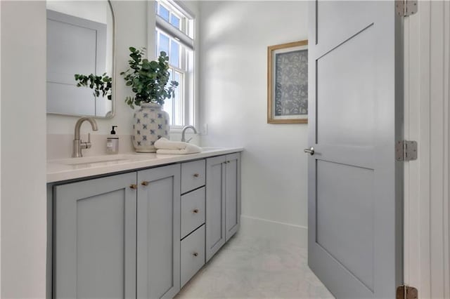 bathroom featuring double vanity, baseboards, and a sink