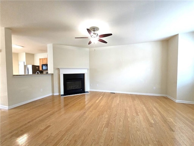 2104 Meadow Peak Rd, Duluth, GA 30097 - unfurnished living room featuring ceiling fan, light wood-style flooring, baseboards, and a glass covered fireplace