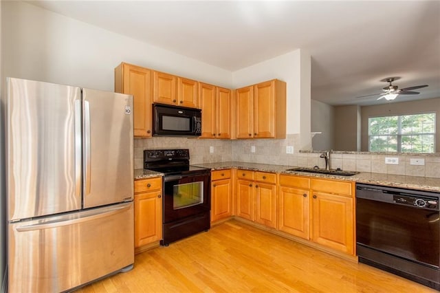 2104 Meadow Peak Rd, Duluth, GA 30097 - kitchen with black appliances, a sink, light wood-style flooring, light stone counters, and decorative backsplash