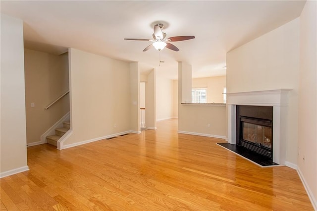2104 Meadow Peak Rd, Duluth, GA 30097 - unfurnished living room with light wood-style flooring, a ceiling fan, stairway, and a glass covered fireplace