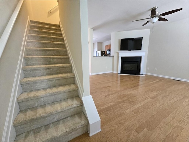 2104 Meadow Peak Rd, Duluth, GA 30097 - stairs with wood finished floors, ceiling fan, baseboards, and a fireplace with flush hearth