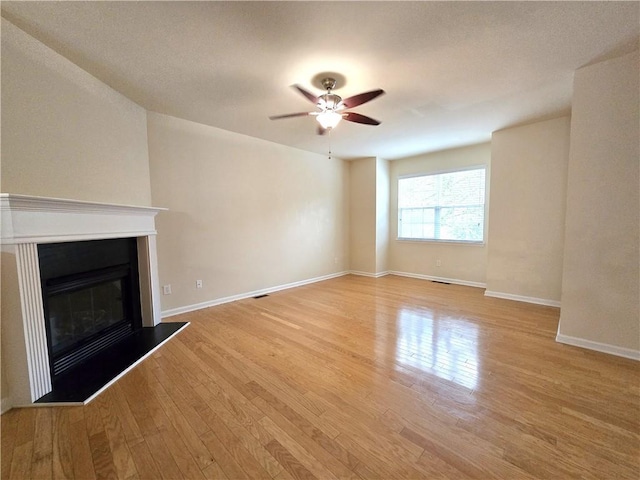 2104 Meadow Peak Rd, Duluth, GA 30097 - unfurnished living room featuring light wood-style floors, a ceiling fan, a glass covered fireplace, and baseboards