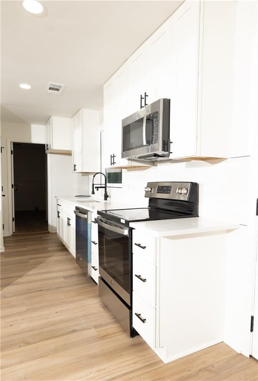 4336 Parkview Dr, Lithia Springs, GA 30122 - kitchen featuring white cabinets, visible vents, light countertops, stainless steel appliances, and a sink