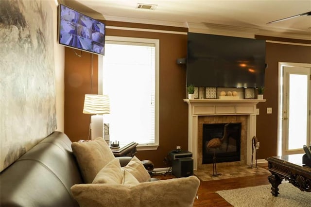 living area featuring a fireplace, hardwood / wood-style floors, ceiling fan, and ornamental molding