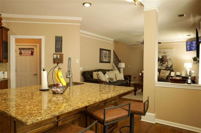 kitchen featuring light stone countertops, ornamental molding, sink, and dark wood-type flooring