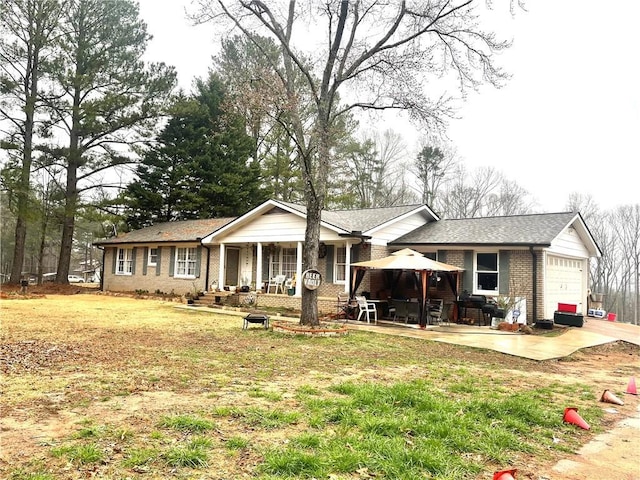 ranch-style home featuring a patio, covered porch, a garage, a gazebo, and a front yard