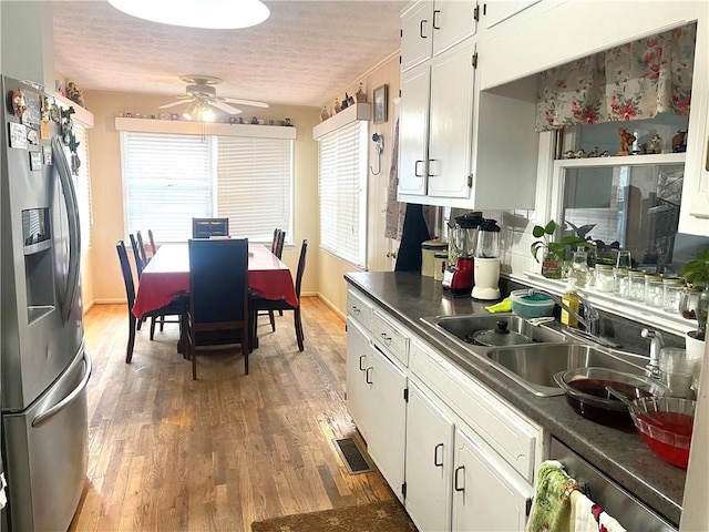 kitchen featuring hardwood / wood-style floors, sink, white cabinets, stainless steel fridge, and a textured ceiling