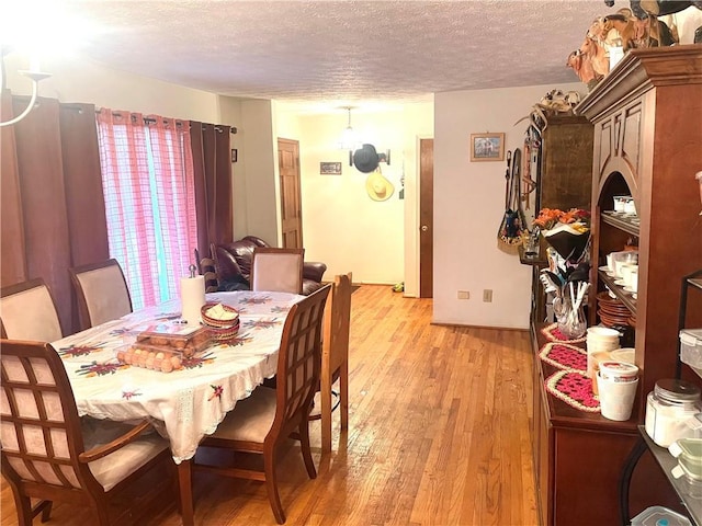 dining area with a textured ceiling and light wood-type flooring