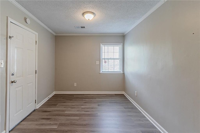 empty room with a textured ceiling, visible vents, wood finished floors, and ornamental molding