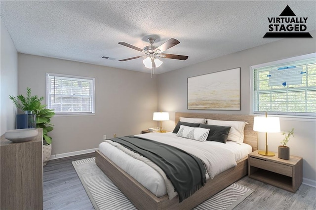 bedroom with visible vents, wood finished floors, and baseboards