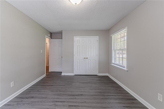 unfurnished bedroom with baseboards, dark wood-style floors, a closet, and a textured ceiling