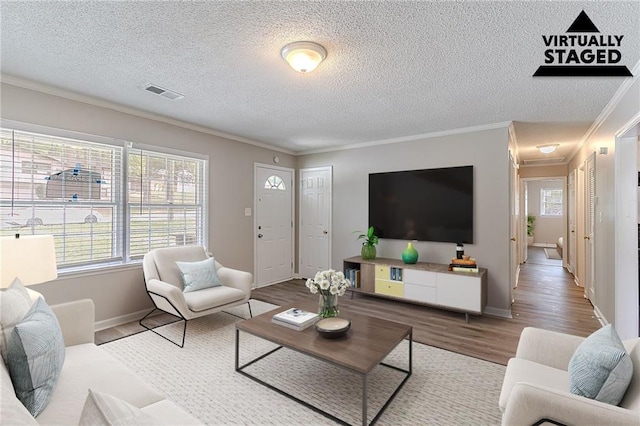 living room with ornamental molding, a wealth of natural light, visible vents, and wood finished floors