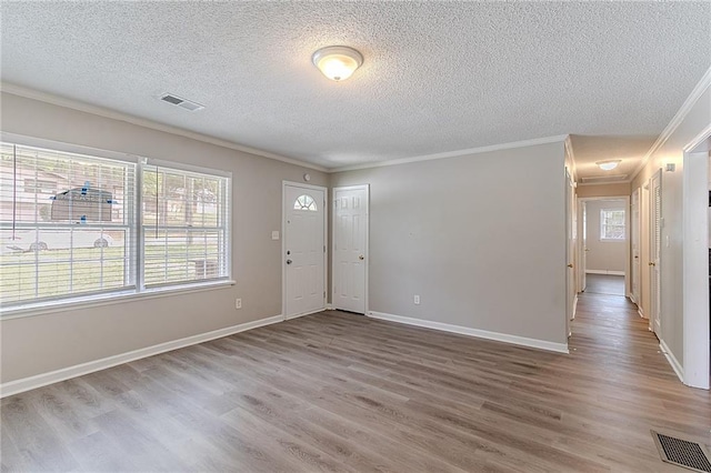 entrance foyer featuring crown molding, visible vents, and wood finished floors