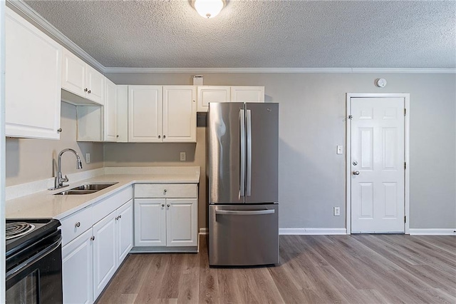 kitchen with a sink, freestanding refrigerator, a textured ceiling, and black range with electric stovetop