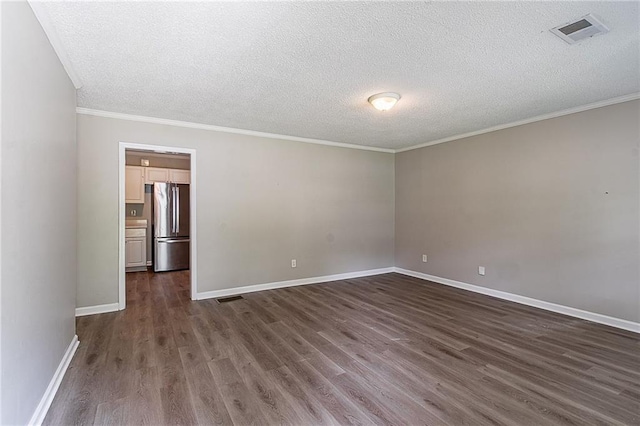 spare room with a textured ceiling, visible vents, baseboards, and dark wood-style floors