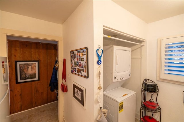 washroom with stacked washer and dryer and dark tile patterned flooring