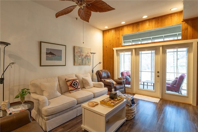 living room featuring dark wood-type flooring, ceiling fan, and a high ceiling