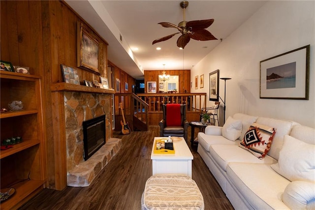 living room featuring dark hardwood / wood-style flooring, ceiling fan with notable chandelier, and a fireplace