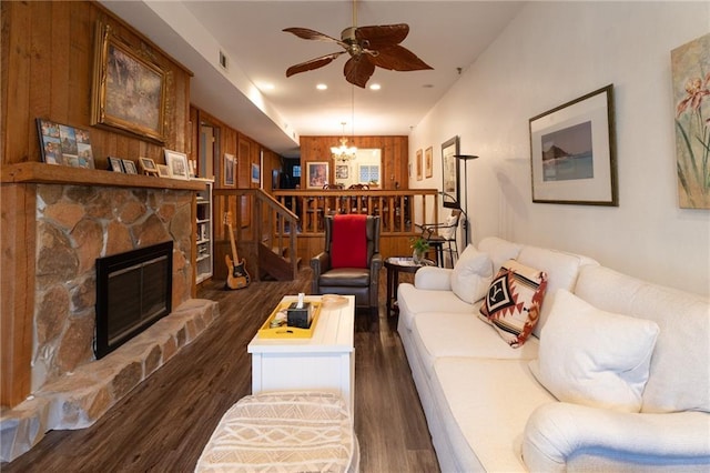 living room featuring dark hardwood / wood-style floors, ceiling fan with notable chandelier, and a fireplace