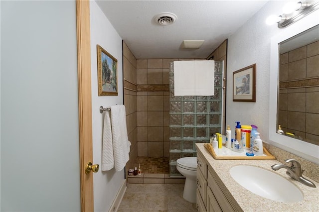 bathroom featuring vanity, tile patterned floors, toilet, and tiled shower